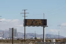 A large digital sign next to a highway. The sign says "Avoid travel. Stay at home. Beat Covid-19."