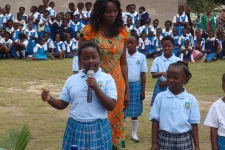 Two girl students and a female teacher during an outdoor performance in Zambia.