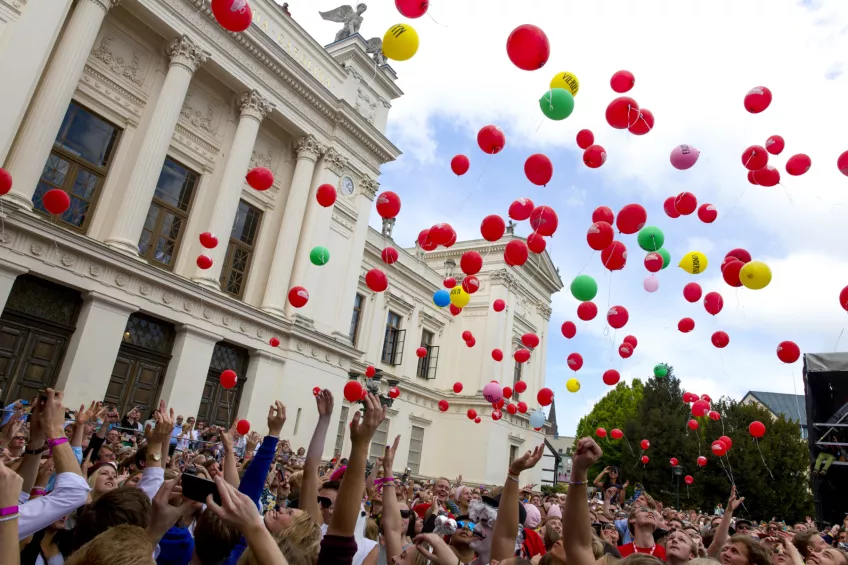 Photo of differently colored balloons in the air outside the university administration buiilding.