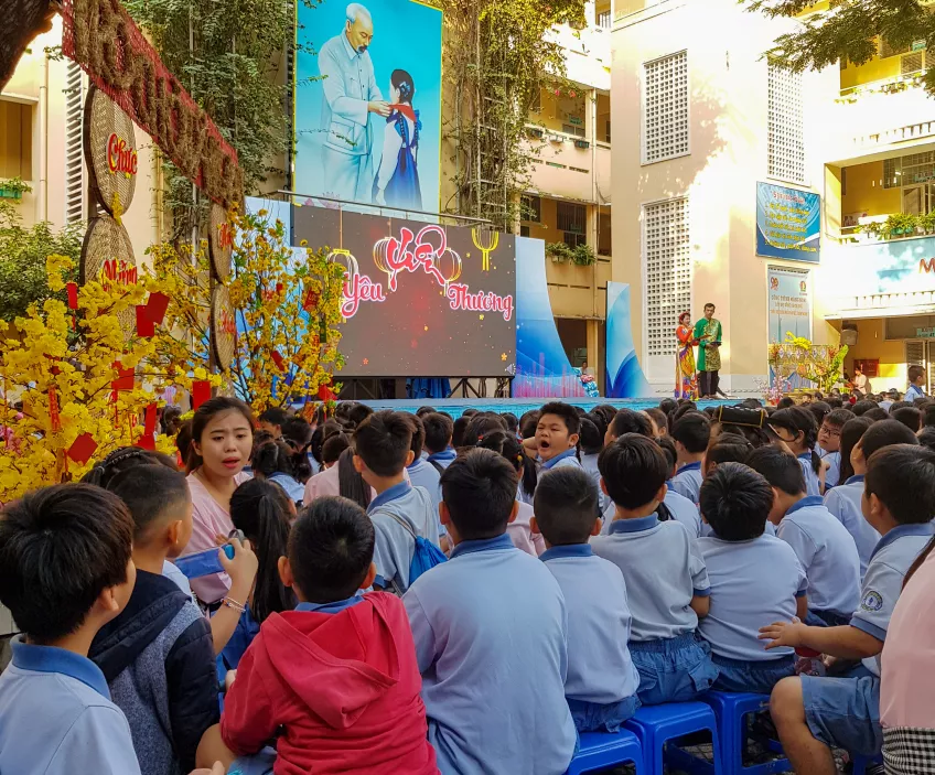 A group of students sitting in front of a stage duringa schoolyard fest in Ho Chi Minh City, Vietnam