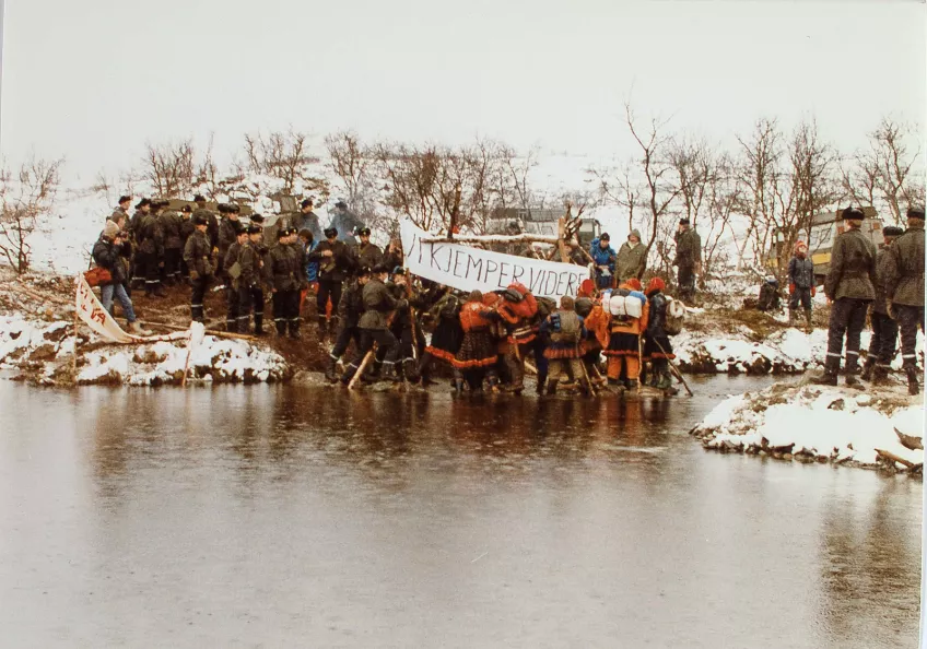 Two groups standing at the edge of a river.