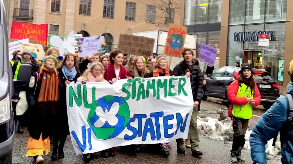ett tjugotal ungdomar håller upp en banderoll som säger "nu stämmer vi staten"