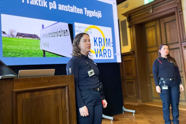 Två personer i uniform står framför en projektorduk.