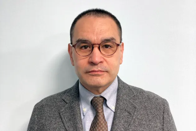 Personporträtt på Timur Dadabaev som bär skjorta, slips, kavaj och glasögon.