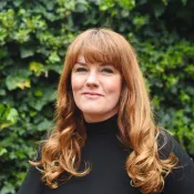 a person with red hair, who is wearing black turtleneck.