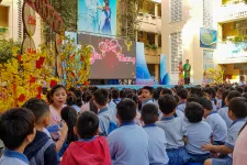 En grupp elever sitter framför en scen under en skolgårdsfest i  Ho Chi Minh City, Vietnam.